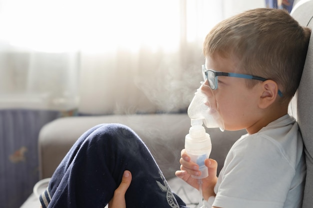 Foto un niño pequeño se sienta con una máscara de inhalación durante la tos y la bronquitis