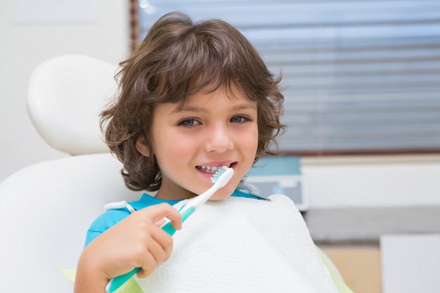 Niño pequeño en silla de dentistas con cepillo de dientes