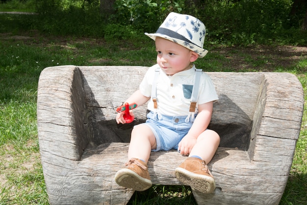 Niño pequeño con sombrero blanco en un banco en el parque