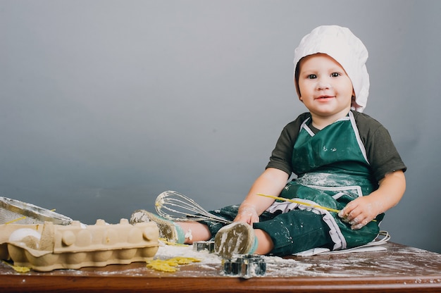 Un niño pequeño con sombrero de cocinero está preparando la cena