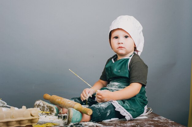 Un niño pequeño con sombrero de cocinero está preparando la cena