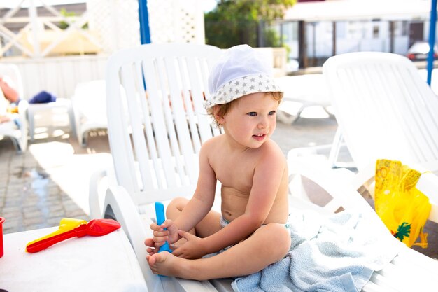 Niño pequeño con sombrero de Panamá juega en verano en un día soleado cerca de la piscina