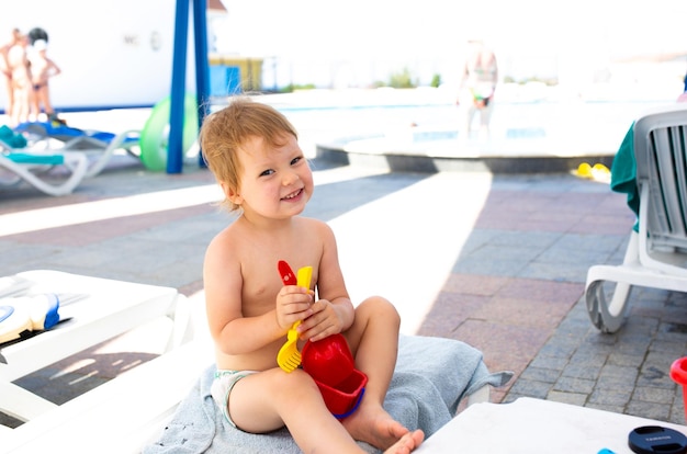 Niño pequeño con sombrero de Panamá juega en verano en un día soleado cerca de la piscina