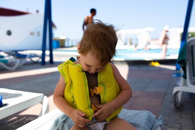 Niño pequeño con sombrero de Panamá juega en verano en un día soleado cerca de la piscina