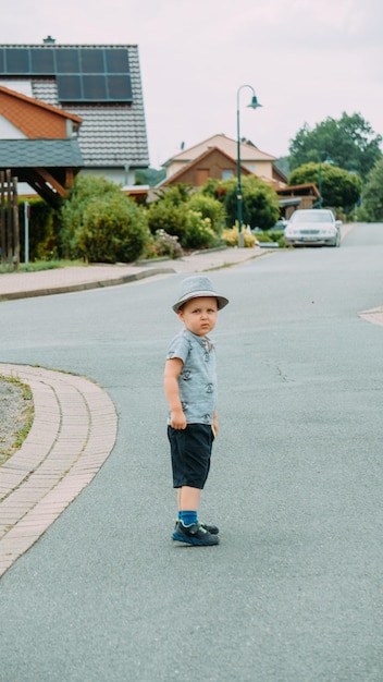 Un niño pequeño con un sombrero y pantalones cortos camina por la calle en un buen día de verano