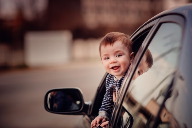 Niño pequeño sonriente mirando por la ventana del coche