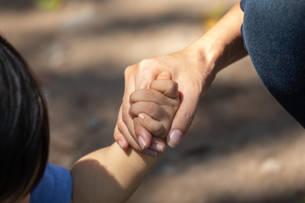 Niño pequeño sosteniendo la mano de la madre miembro de la familia como una familia unida