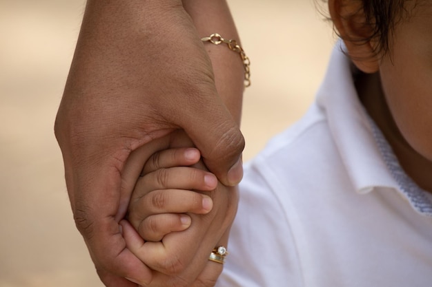 Niño pequeño sosteniendo la mano de la madre miembro de la familia como una familia unida