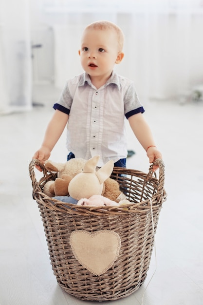 Foto un niño pequeño sostiene una canasta con juguetes. el concepto de infancia