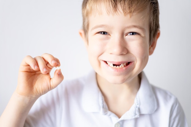 Un niño pequeño sostiene en su mano su primer diente de leche caído El niño crece los dientes se caen Cuidado de los dientes de leche y la cavidad bucal