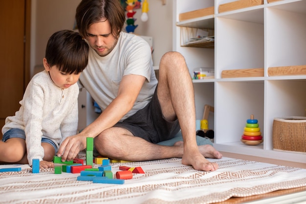 Niño pequeño y su padre jugando en casa con bloques de construcción de madera. Educación en el hogar. Quédate en casa. Tiempo familiar