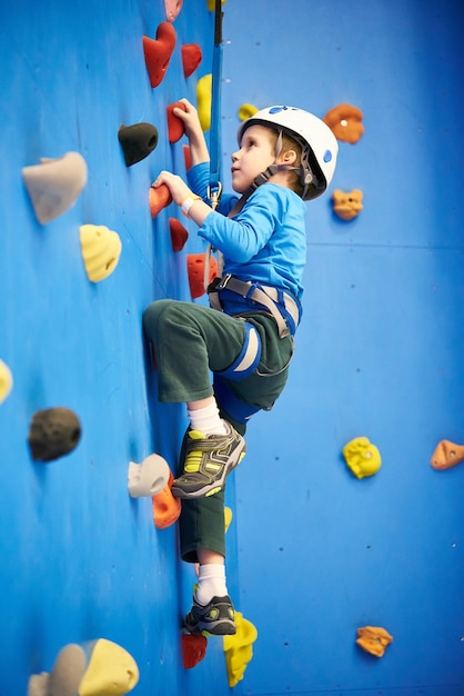 Foto el niño pequeño está subiendo al parque de atracciones en la pared azul