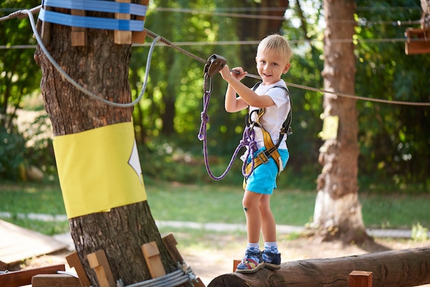 El niño pequeño supera el obstáculo en el parque de la cuerda.