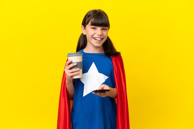 Niño pequeño superhéroe aislado en un fondo morado sosteniendo café para llevar y un móvil