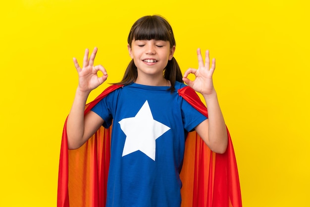 Niño pequeño superhéroe aislado sobre fondo púrpura en pose zen