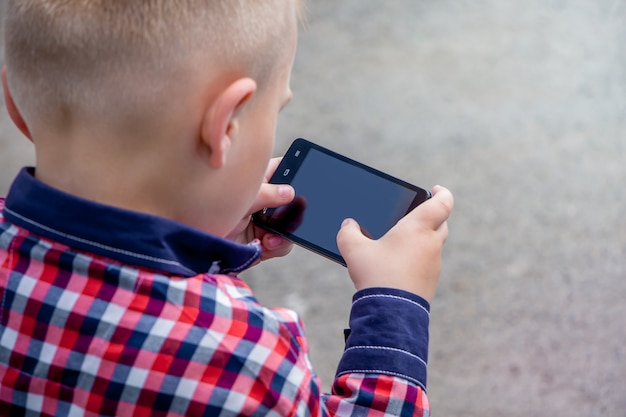 Niño pequeño con teléfono inteligente en sus manos