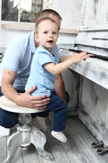 Un niño pequeño toca el piano con su papá.