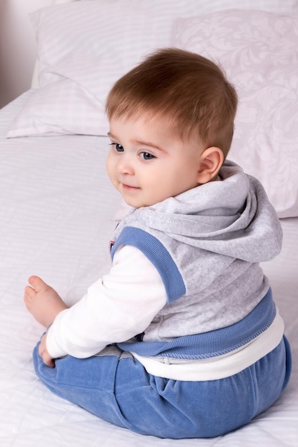 Un niño pequeño con traje azul se sienta de espaldas a la cámara.