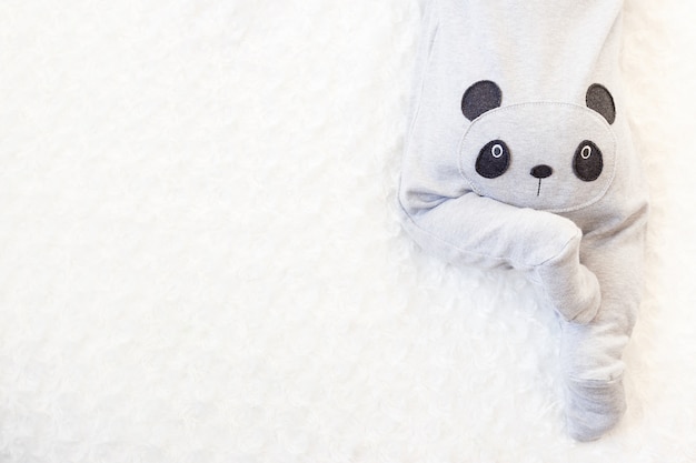Niño pequeño en un traje de panda se encuentra en la cama. culo bebé