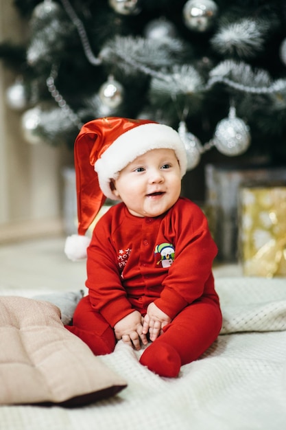 Un niño pequeño con traje rojo se sienta en el suelo.