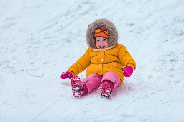 Niño pequeño en trineo deslizándose por la colina de invierno