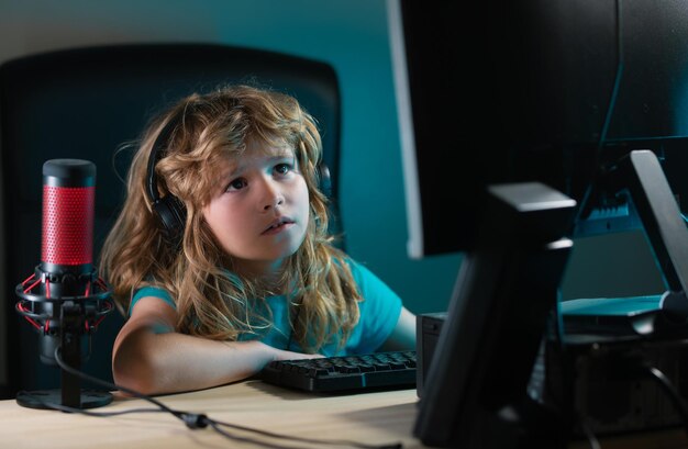Un niño pequeño usa un escritorio por la noche un niño con una pantalla de computadora en la habitación con un rayo de neón Retrato de un niño lindo mientras escribe en el teclado