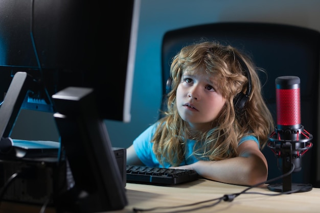 Un niño pequeño usa un escritorio por la noche un niño con una pantalla de computadora en la habitación con un rayo de neón Retrato de un niño lindo mientras escribe en el teclado