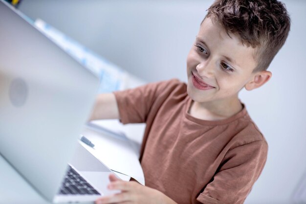 Niño pequeño usando portátil para la tarea Educación a distancia