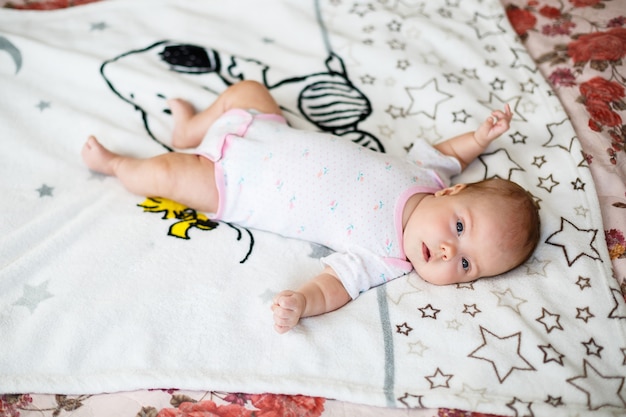 Un niño pequeño yace sobre una sábana blanca. Ropa de bebé que yace en la cuna.