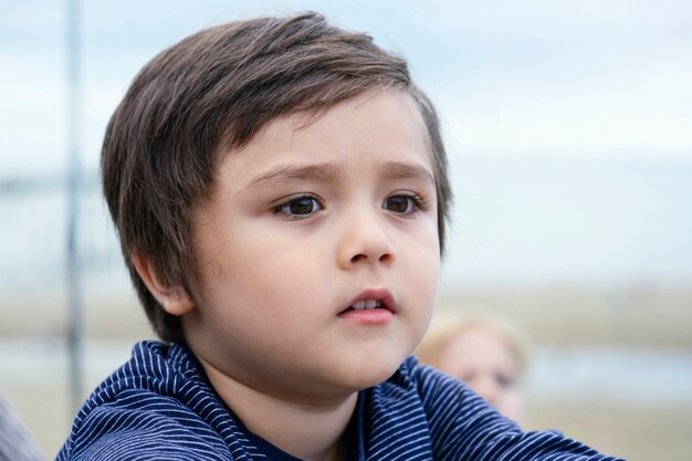 El niño perdido en sus pensamientos mirando con fondo borroso con vistas al mar