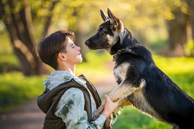 Un niño con un perro camina en el parque en una soleada tarde de primavera se sienta en la hierba el perro besa al dueño La amistad del hombre y el estilo de vida saludable de los animales