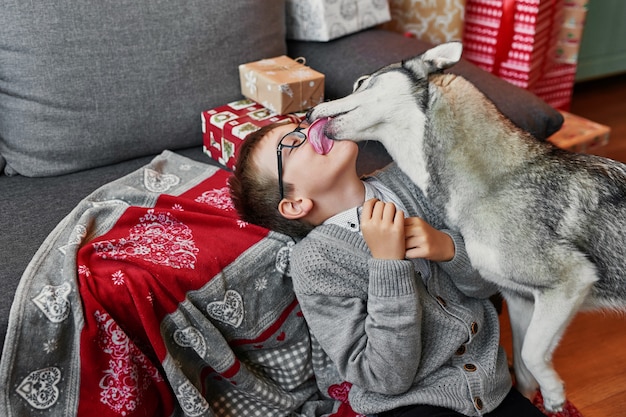 Niño con perro cerca del árbol de Navidad sobre fondo de Navidad