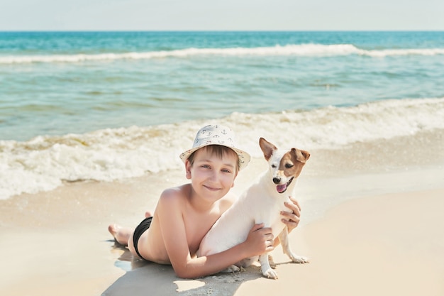 Niño con perro jack russel en la playa