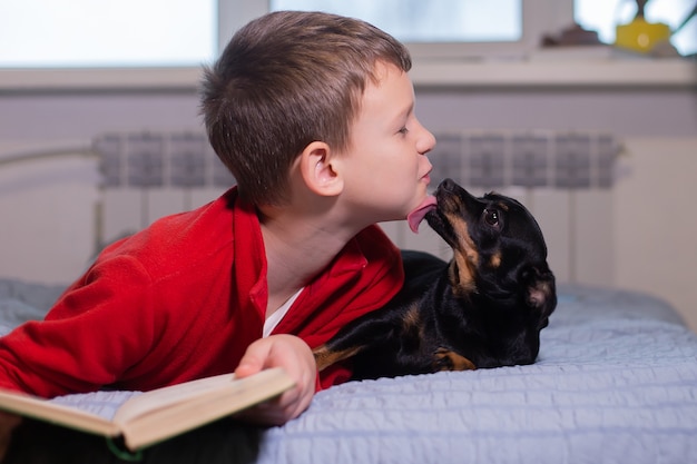 El niño con perro lee un libro.