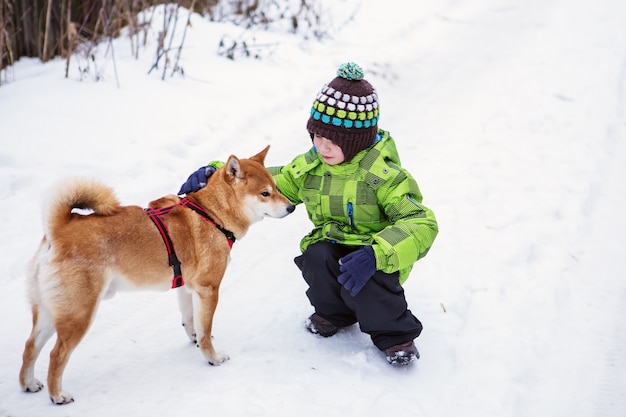 Niño con perro Shiba Inu al aire libre en invierno