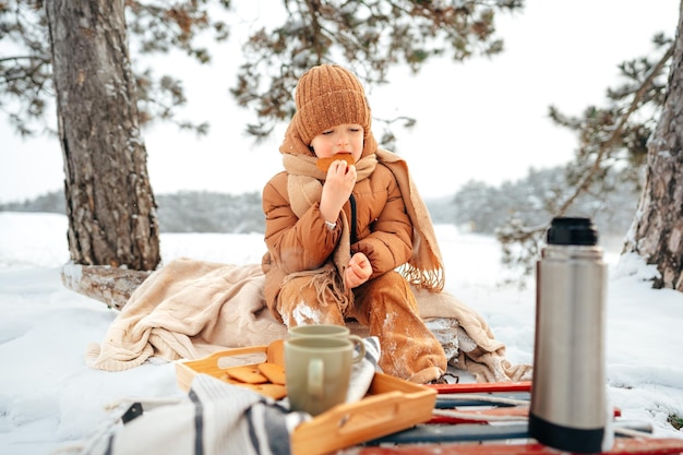 Niño en un picnic en el bosque de invierno