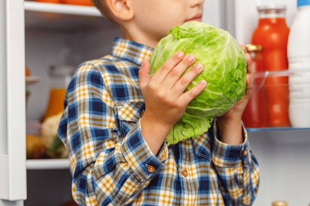 Niño de pie cerca de la nevera abierta