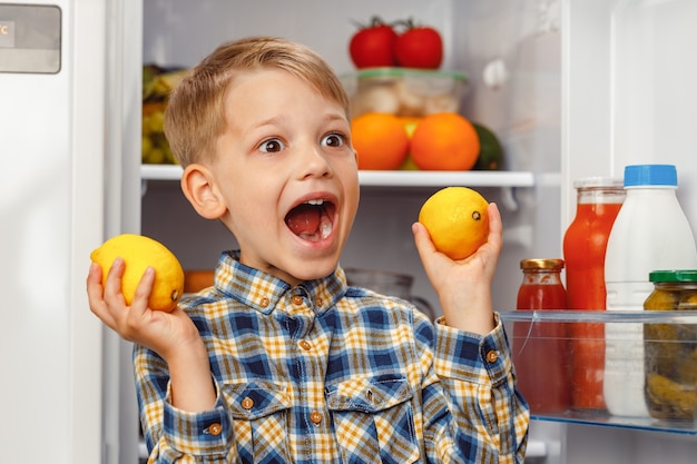 Niño de pie cerca de la nevera abierta