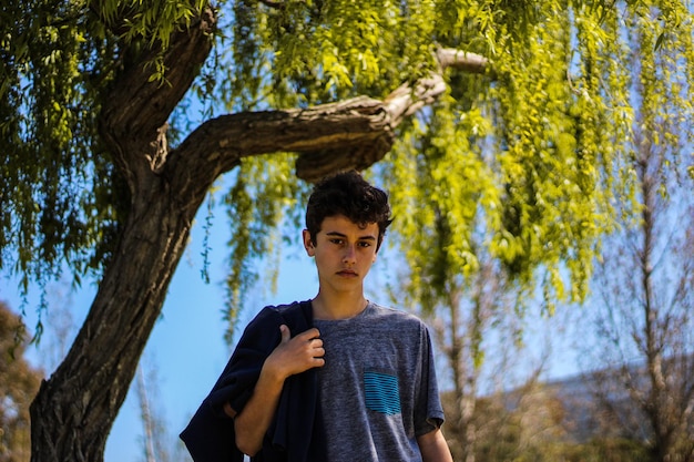 Niño de pie junto al árbol