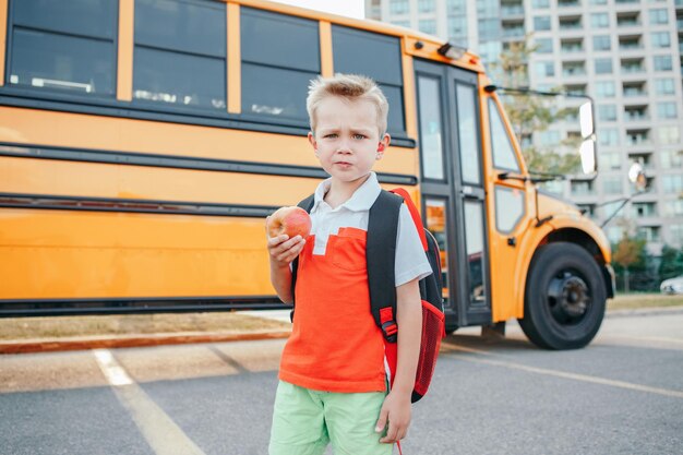 Foto niño de pie junto al autobús en la calle
