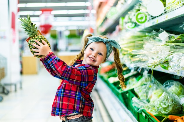 Niño de pie con piña en el supermercado