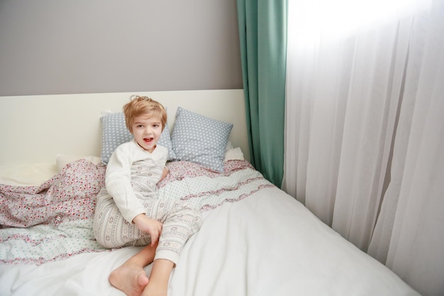 Un niño en pijama yace en una cama cubierta con una sábana blanca.