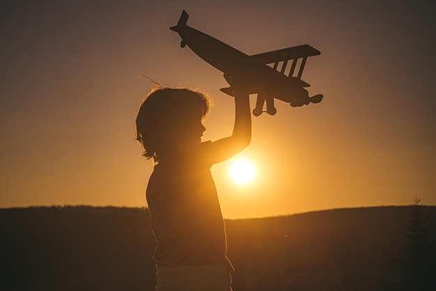 Niño piloto aviador con avión sueña con viajar al atardecer.