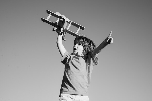 Niño piloto con avión de juguete contra el fondo del cielo Niño feliz jugando al aire libre Infancia feliz Soñar despierto Sueños de niños