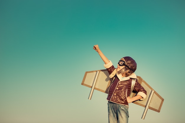 Niño piloto con jet pack de juguete contra el fondo del cielo otoñal. niño feliz jugando al aire libre