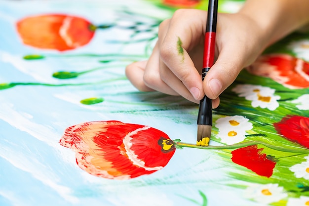 Foto niño pinta amapolas y manzanillas por gouache