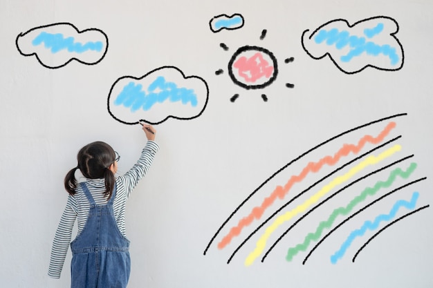 El niño pinta un arco iris en la pared de la cuarentena introducida por coronavirus como símbolo de esperanza para el fin de la pandemia de coronavirus. Dibujo infantil de un arco iris