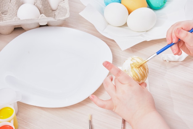 Niño pinta huevo de Pascua en una mesa de madera