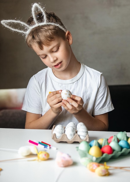 Foto niño pinta huevos con diferentes colores.