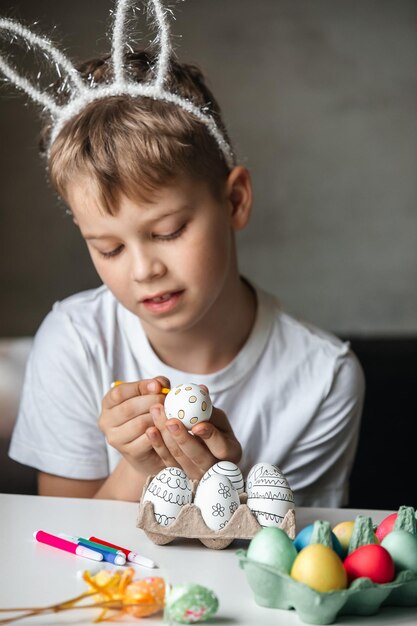 Foto niño pinta huevos con diferentes colores.